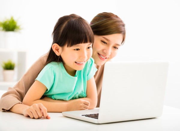 Girl looking into laptop with mother